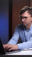 vertical Scientist typing on laptop with microscope nearby in home office video