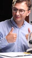 vertical Scientist gesturing thumbs up with microscope in laboratory video
