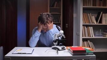 Stressed scientist suffering headache touching head at workplace video