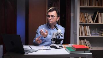 Scientist analyzing sample in laboratory with microscope and laptop video