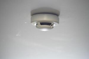 Smoke detector installed on a ceiling indoors photo