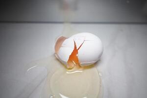 Cracked egg spills yolk on a smooth surface photo