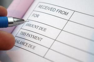 Hand writing in a receipt document with a blue pen photo