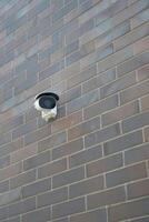 Outdoor security camera mounted on a brick wall photo