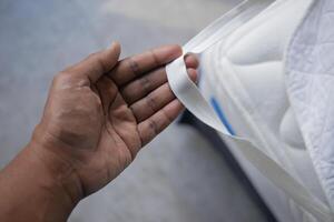 Hand Holding a Mattress Strap While Preparing Bedding for Setup photo