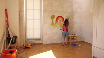 A young girl painting a rainbow on a wall video