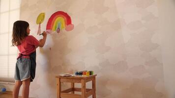 Young girl painting rainbow on wall in playroom video