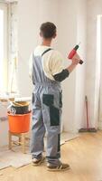 A man in overalls is holding a drill in a room video