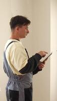 A man in overalls is holding a tablet computer video