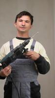 A man holding a drill and wearing overalls video