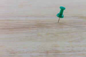 A green push pin on a wooden table photo