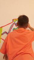 A boy painting on a wall with a red and yellow line video