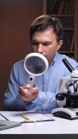 vertical Scientist examining sample with magnifying glass in laboratory video