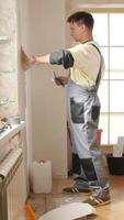 Vertical construction worker removing wallpaper during renovation works video