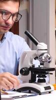 vertical Scientist working with microscope in laboratory researching new medicine video