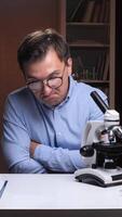 vertical Scientist feeling frustrated looking at microscope in laboratory office video