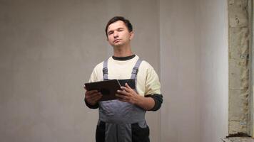 Construction worker in overalls writing notes on a clipboard while inspecting a newly renovated room in a house under construction, ensuring quality and compliance with plans video