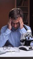 vertical Stressed scientist suffering headache working at night in laboratory video