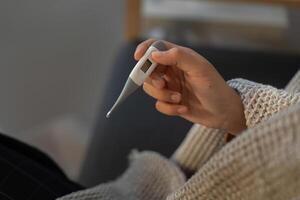 Fever Monitoring. Individual checking temperature with thermometer. photo