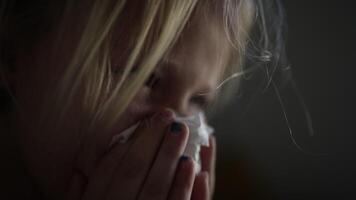 Young blonde girl is holding tissue to her face, expressing emotions in a softly lit setting, highlighting her vulnerability and the intimate moment of reflection video
