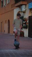 Teenager steps on metal sphere and jumps off while walking in urban street wearing casual beige clothes video