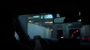 Driver holding steering wheel inside car while approaching tunnel with blurry lights outside video