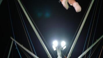 Young girl flipping upside down in air on nighttime bungee trampoline ride with lights video