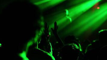 People are clapping and cheering during a live music concert, illuminated by green stage lights, creating a vibrant and energetic atmosphere video