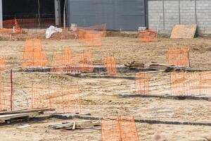 Unfinished building project with dirt, concrete, and safety netting. photo