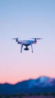 Drone with camera flying against colorful sunset sky over mountain landscape for aerial photography and videography during golden hour twilight scenery. photo