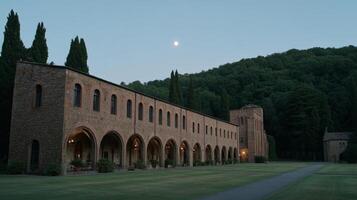 Tranquil Evening at Historic Abbey Surrounded by Lush Green Hills and Moonlight Glowing in the Sky photo