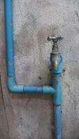 Blue PVC Water Pipes and an Old Faucet on a Concrete Wall photo