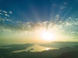 Dazzling sun in the evening sky illuminates all the peaks of the photo