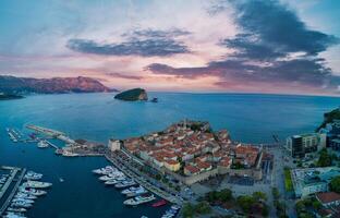 Panorama of port with boats for excursions on the Adriatic Sea near the island of St. Stevan in the evening city of Budva photo