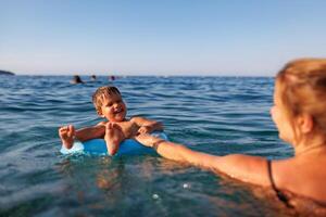 Caring mother rides her son on an inflatable ring in the seaMother rides son on inflatable ring in seaMother rides son on inflatable ring in sea photo