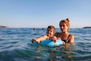 Caring mother rides her son on an inflatable ring in the seaMother floats son on inflatable ring in sea photo