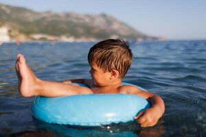 A little boy swims with an inflatable ring in the sea photo