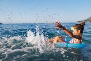 Cheerful girl sits in an inflatable circle and splashes with watCheerful girl splashes in inflatable circle water photo