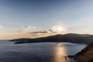 Dazzling sun in the evening sky illuminates all the peaks of the Balkan Montenegrin mountains and the coast of Kotor BayDazzling evening sun lights up Balkan mountains photo