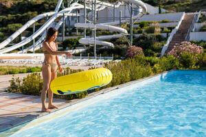 A teenage girl stands at the edge of the pool and throws a large photo