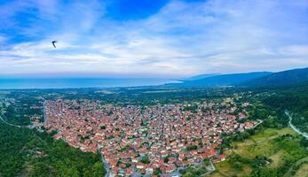 Panorama of Greek town of Litochoro with small houses and green vegetation against the backdrop of the Aegean Sea and a cloudy sky photo