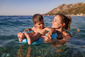 Caring mother rides her son on an inflatable ring in the seaMother rides son on inflatable ring in seaMother rides son on inflatable ring in seaMother rides son on inflatable ring sea photo