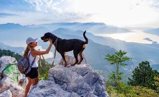 A sporty girl with a backpack stands on the edge of a mountain wSporty girl with backpack standing on mountain edge photo