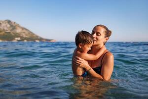 Cheerful mother plays with her son in the seaMother plays happily with son in sea photo