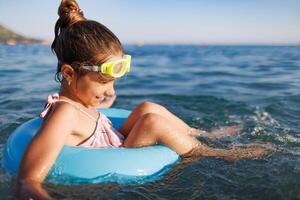 Cheerful girl sits in an inflatable circle and splashes with watCheerful girl splashes in inflatable circle with water photo
