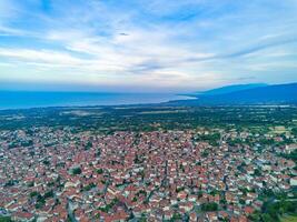 Greek town of Litochoro with small houses and green vegetation against the backdrop of the Aegean Sea and a cloudy sky photo