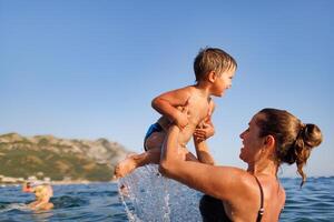 Cheerful mother plays with her son in the seaCheerful mother plays with son seaCheerful mother plays with son at sea photo