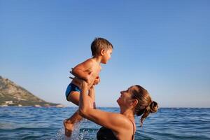 mother plays with her son in the seaMother plays happily with son in sea photo