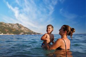 Cheerful mother plays with her son in the seaCheerful mother plays with son seaMother and son play in the sea photo
