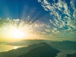 Dazzling sun in the evening sky illuminates all the peaks of the Balkan Montenegrin mountains and the coast of Kotor Bay photo